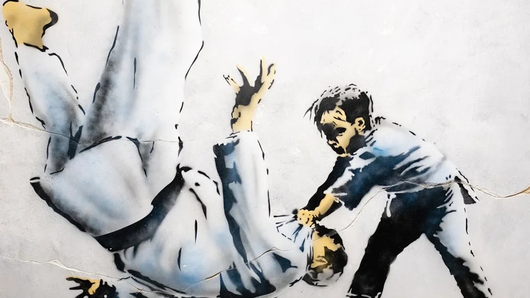 Street art of a child flipping an adult, featured in The World of Banksy exhibit, Lisbon.