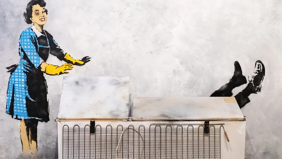 Street art of a woman pushing a man into a freezer at the Banksy Museum in Lisbon.