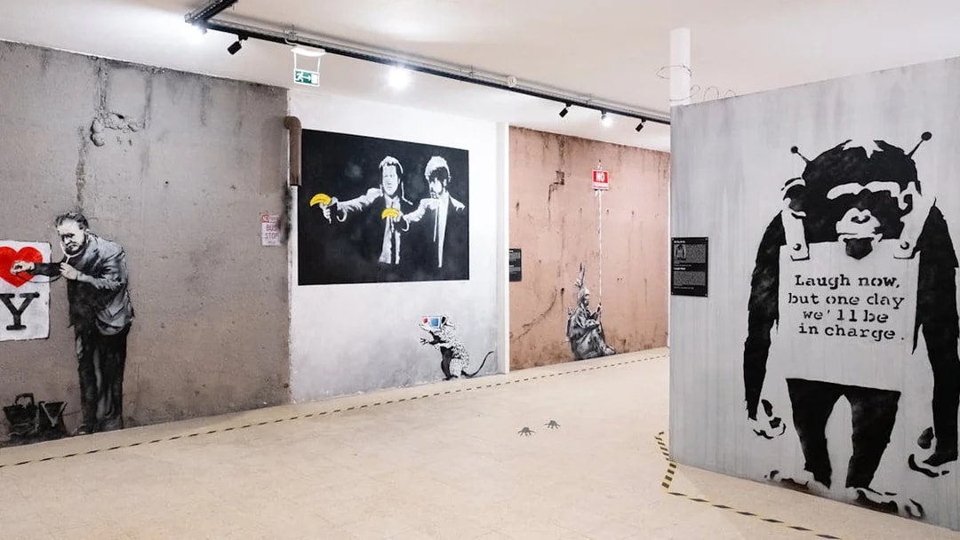 Banksy artwork in Lisbon museum featuring iconic graffiti and stencils.