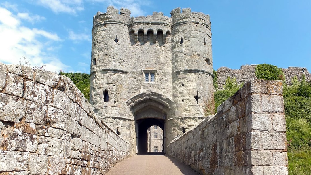 Carisbrooke Castle entrance with stone walls and towers under a blue sky.