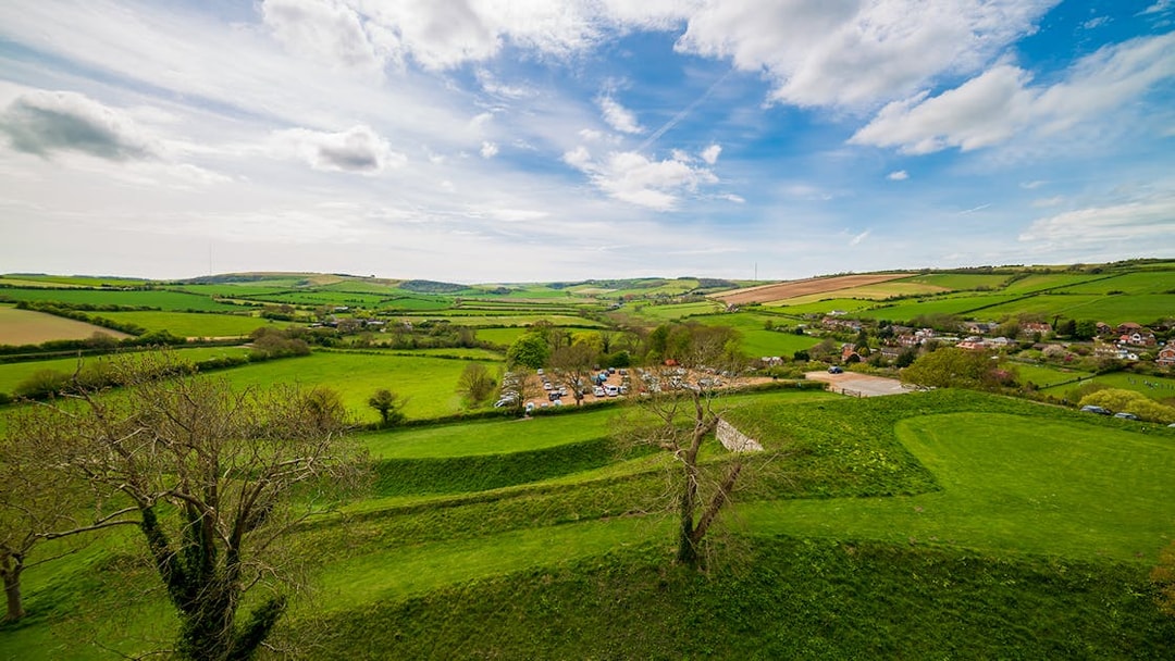 Carisbrooke Castle grounds with lush green fields and distant village view.