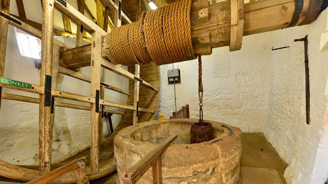 Carisbrooke Castle well house with historic wooden wheel and rope mechanism.