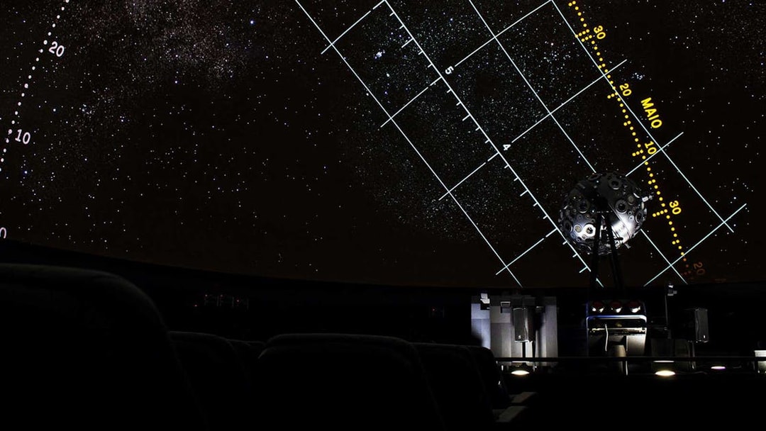 Starry projection inside Navy Planetarium with celestial grid lines.