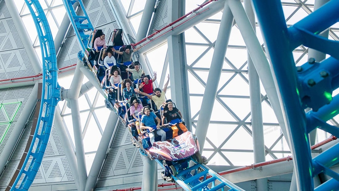 Riders on The Storm Coaster Dubai during a thrilling loop inside a modern structure.