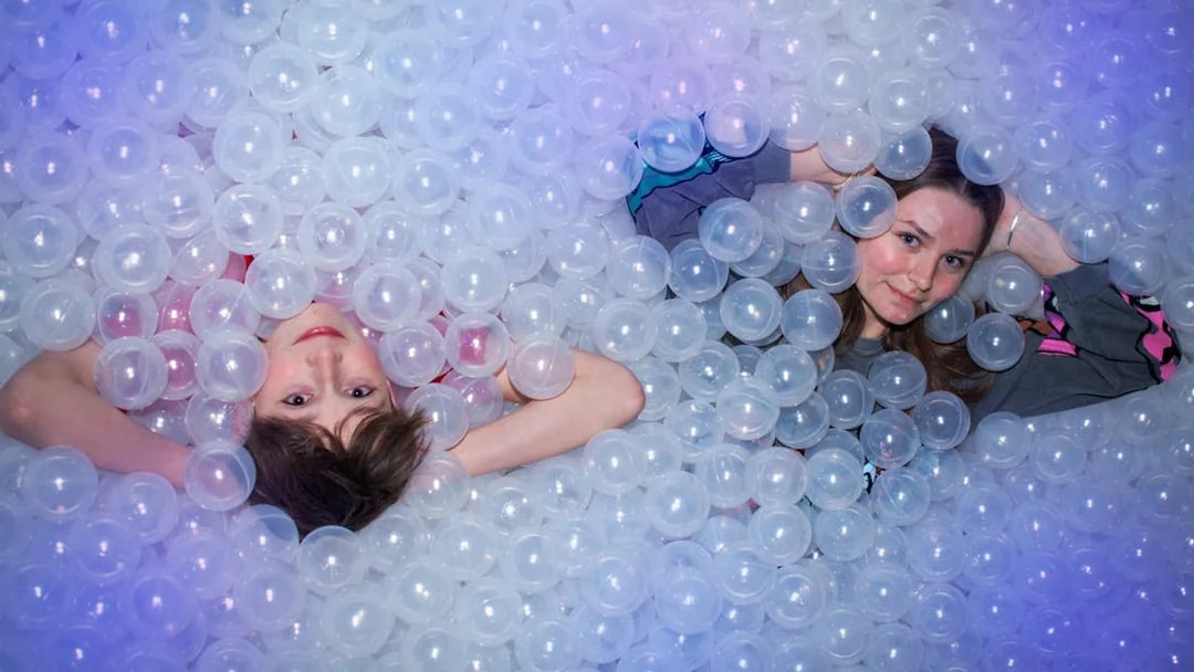 People lying in a ball pit at The TUBE attraction.