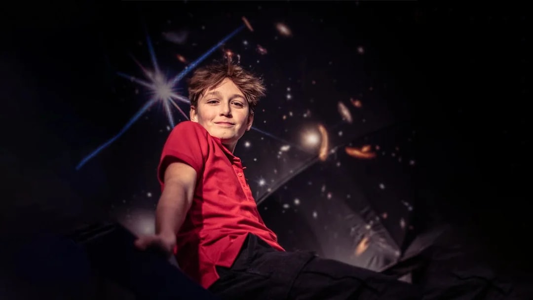 Child enjoying The TUBE experience in Copenhagen with a cosmic backdrop.