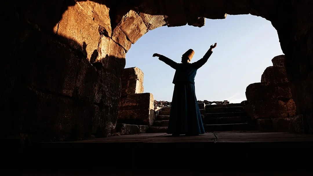 Whirling dervish performing in ancient stone archway, Cappadocia.
