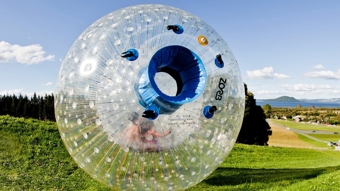 Zorb inflatable ball on a grassy hill with scenic landscape in the background.