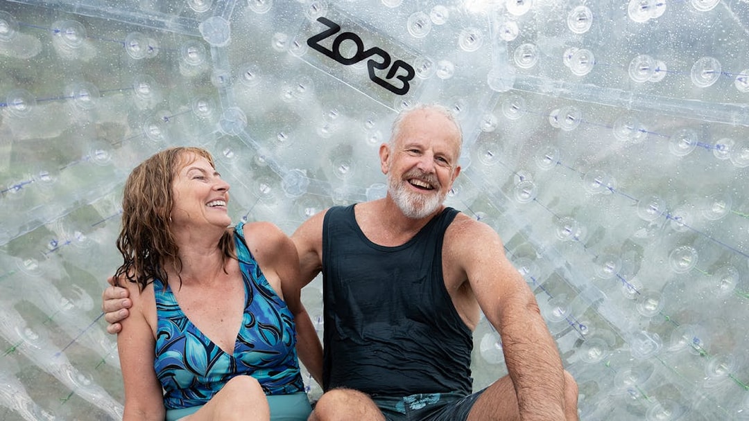Couple enjoying Zorb giant inflatable ball ride experience.
