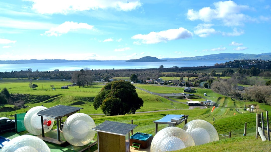 Zorb giant inflatable balls on a hillside with scenic view of Lake Rotorua, New Zealand.