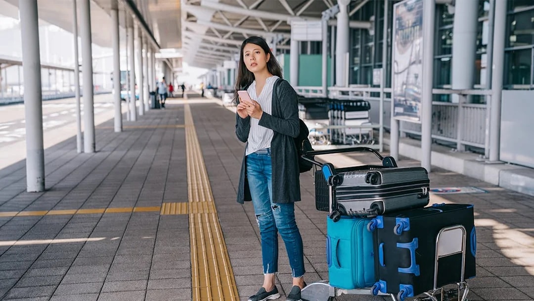 Traveler with luggage at Tirana Airport bus terminal for Durres transfer.