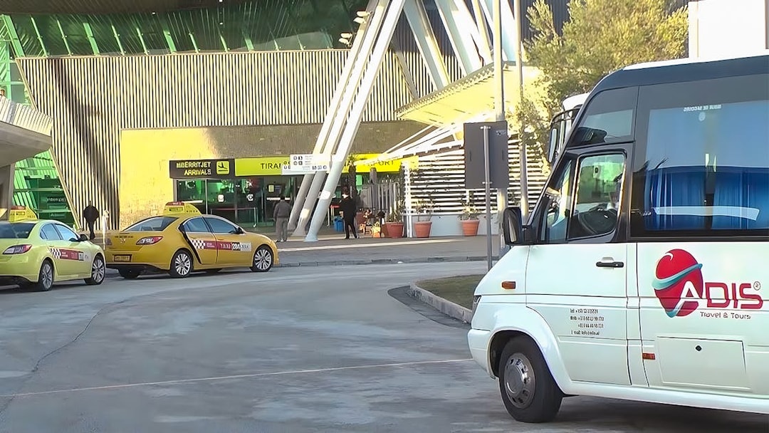 Bus and taxis at Tirana Airport entrance for Durres transfer service.