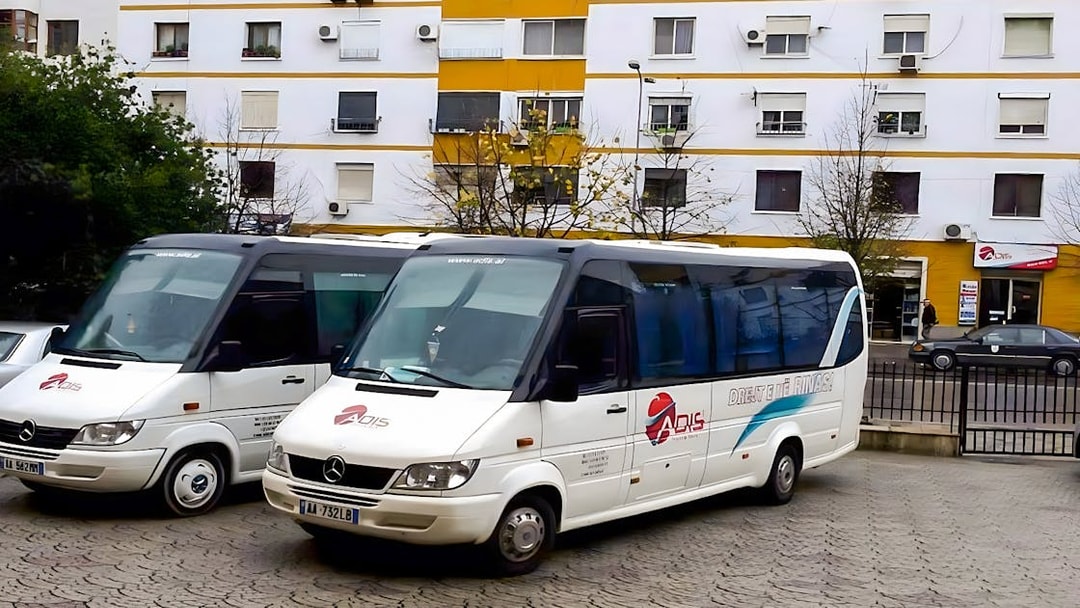 Buses parked outside a building for Tirana Airport transfer to Durres.