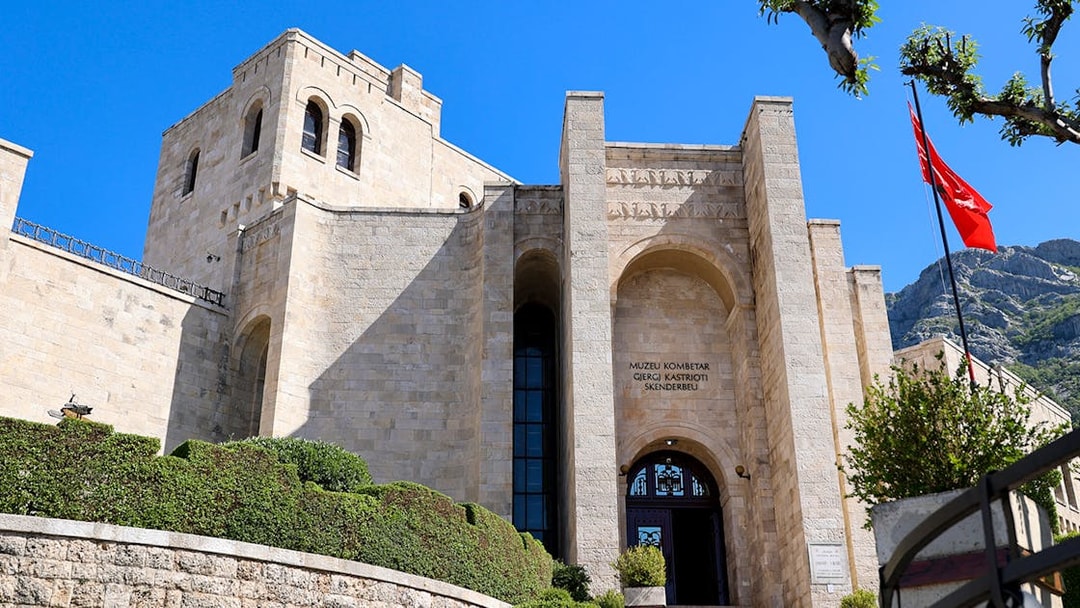 Skanderbeg Museum entrance with stone facade and Albanian flag in Krujë, Albania.