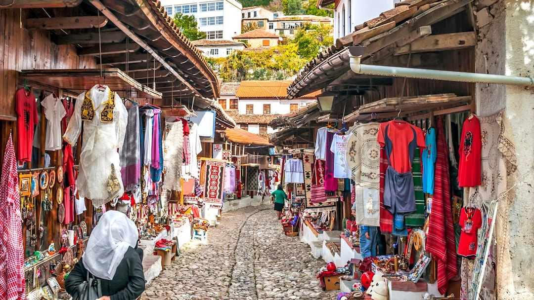 Cobblestone street with traditional market stalls in Old Town Kruja, Albania.