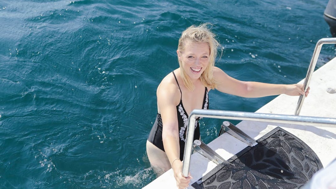Female guest climbing boat ladder during Kotor tour.