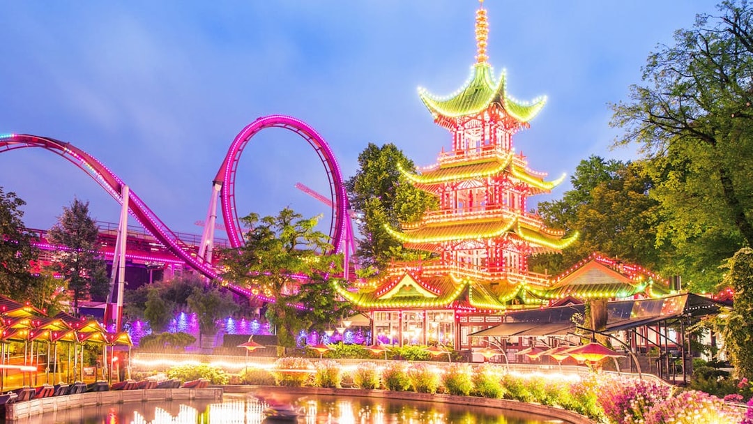 Tivoli Gardens illuminated pagoda and roller coaster at dusk.
