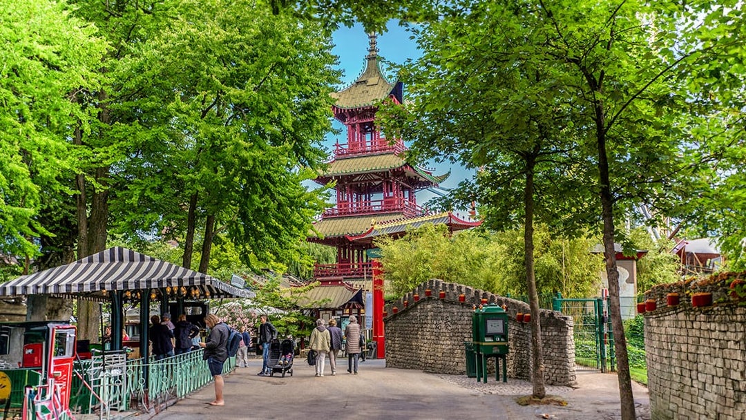 Pagoda temple in Tivoli Gardens, Copenhagen, surrounded by trees and visitors exploring the area.