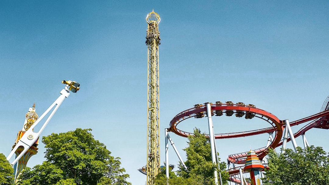Tivoli Gardens roller coasters and rides against a clear blue sky in Copenhagen.