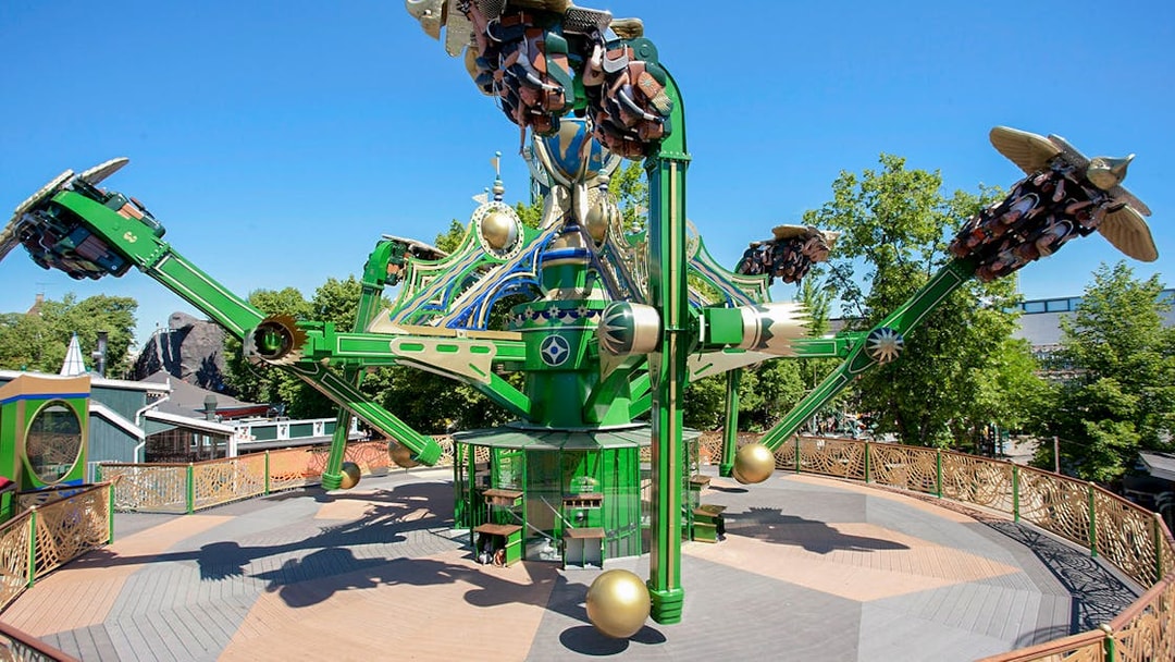 Aquila ride at Tivoli Gardens with passengers on rotating arms against a clear sky.