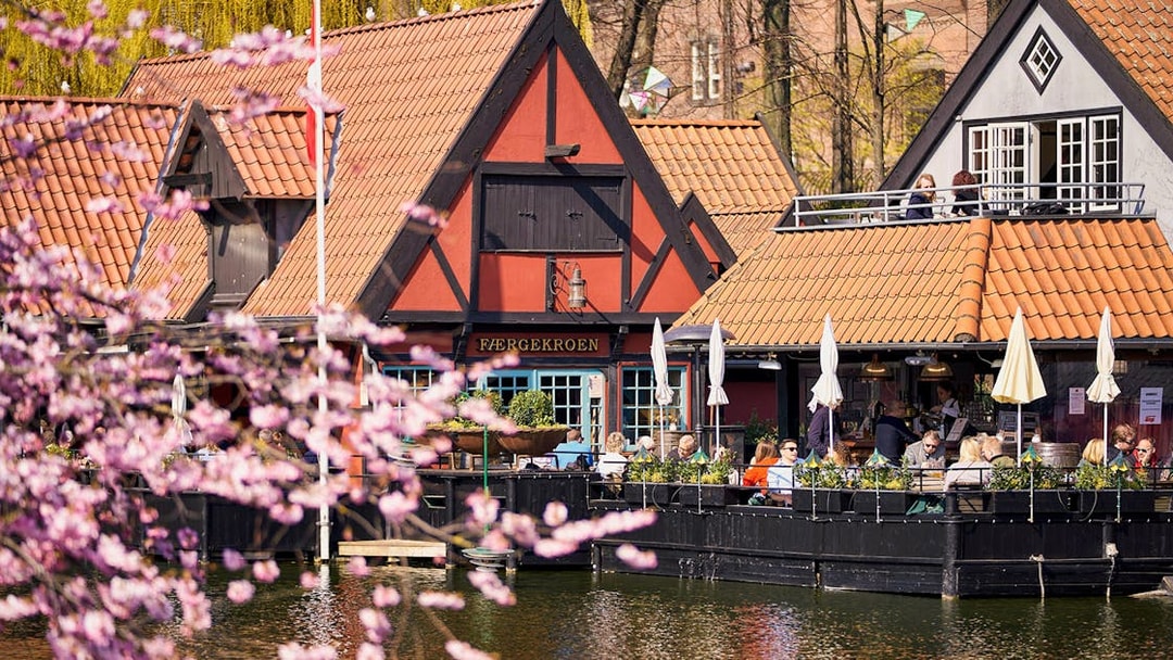 Tivoli Gardens lakeside restaurant with people dining outdoors in Copenhagen.