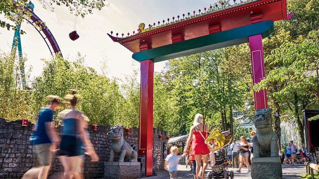 Visitors walking under a colorful archway at Tivoli Gardens, Copenhagen.