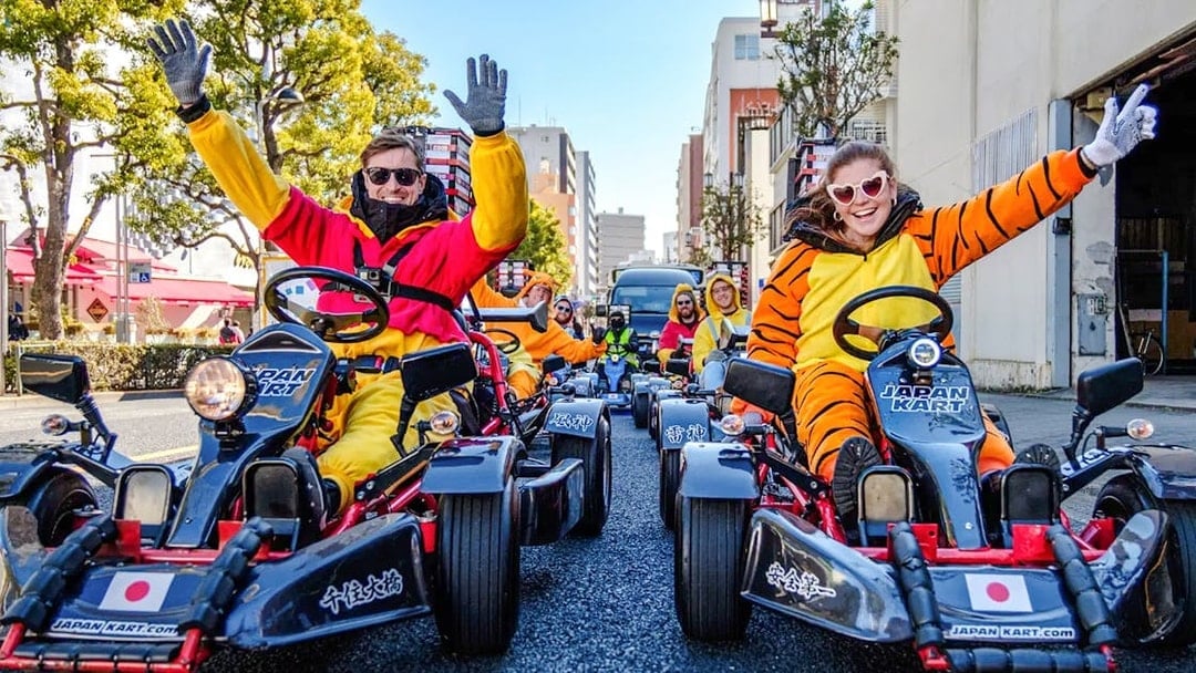 People in costumes driving go-karts on Asakusa streets during a tour.