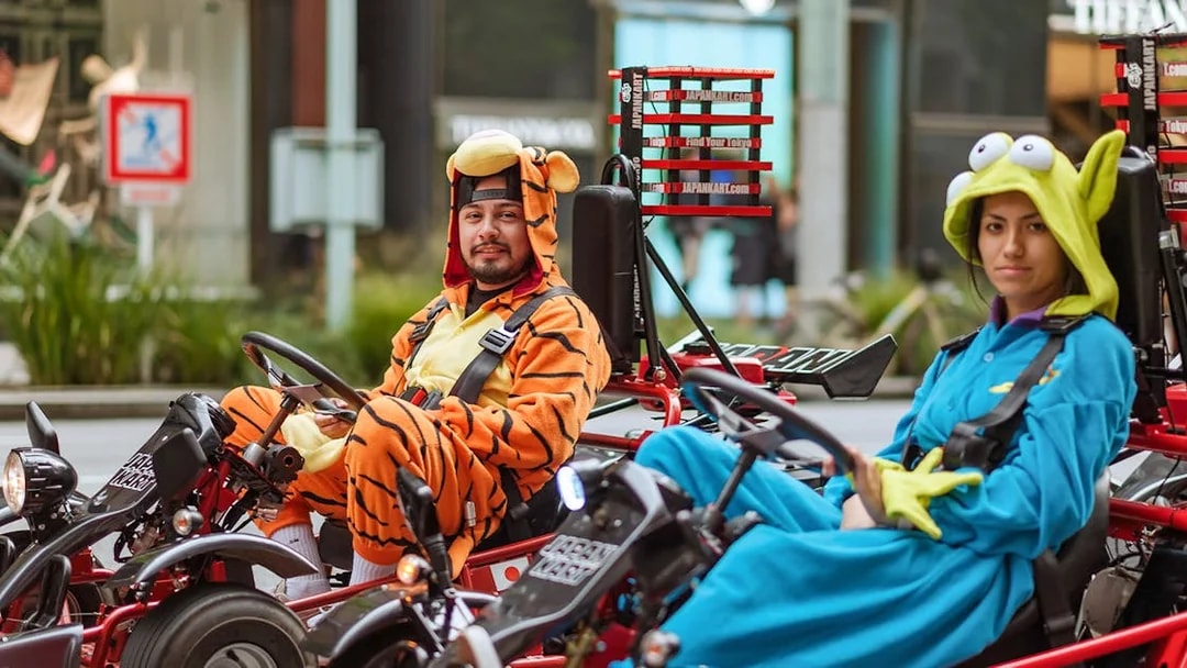 Couple in costumes driving go-karts on Asakusa tour, Tokyo.