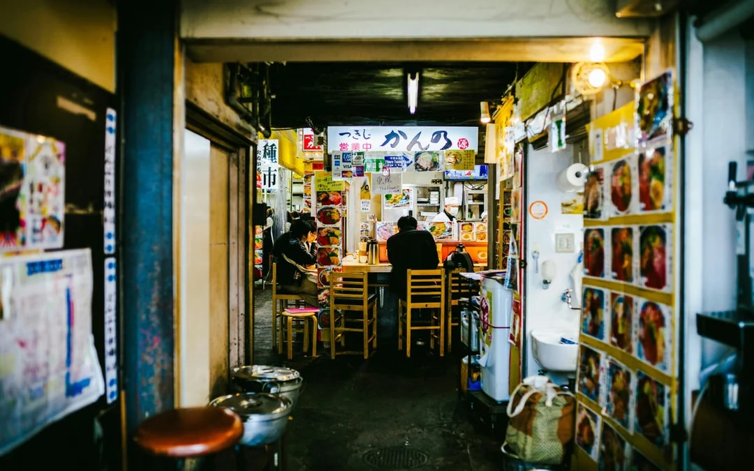 Dining area in Tsukiji Outer Market, Tokyo, with patrons seated at a small eatery.