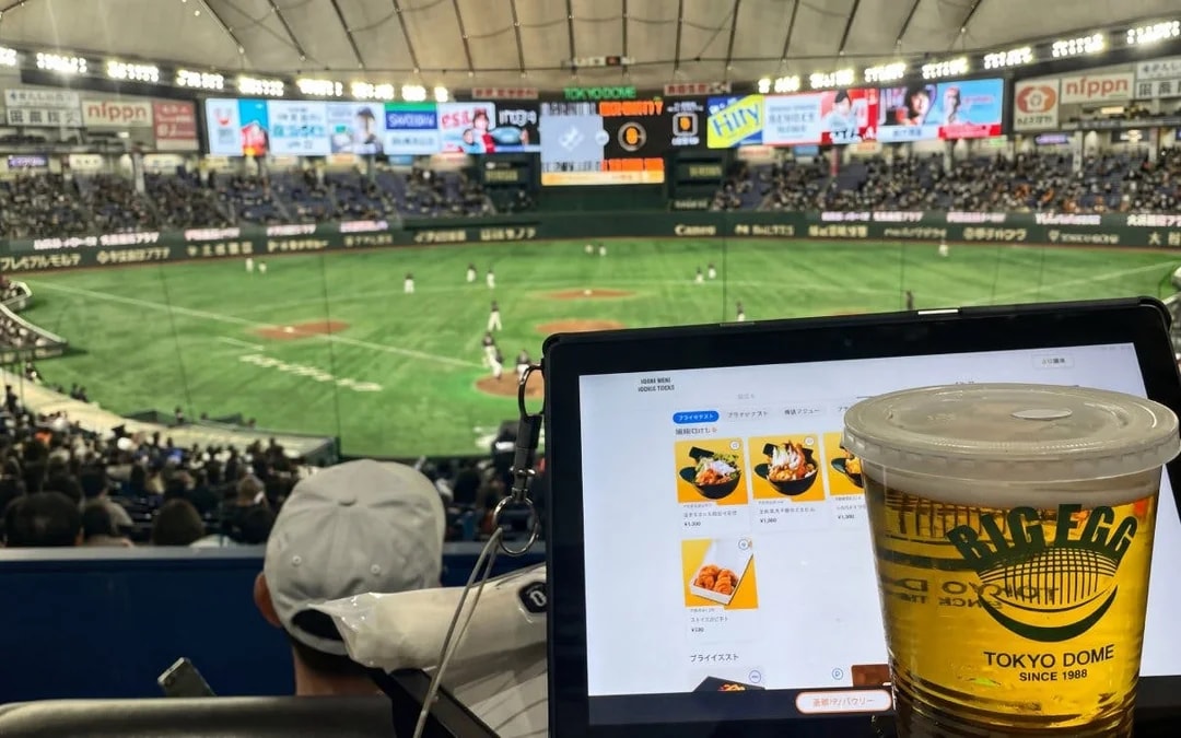Baseball game at Tokyo Dome with a tablet menu and beer in the foreground.