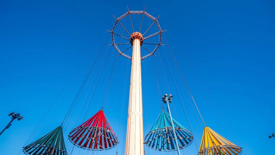 Colorful swing ride at Tokyo Dome City Attractions against a clear blue sky.