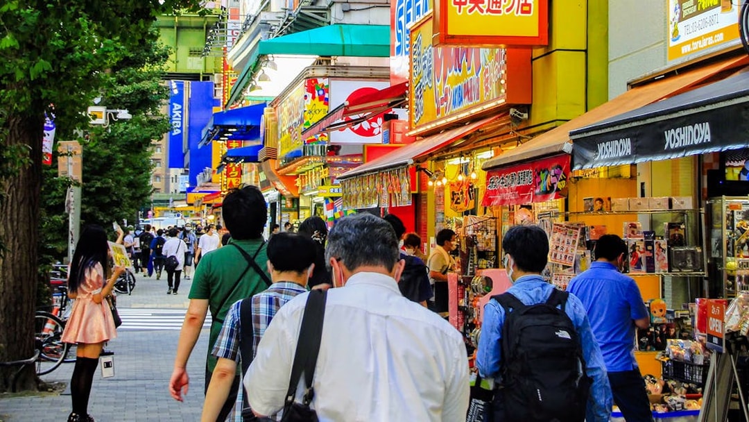Crowded street in Akihabara, Tokyo with colorful shop signs and people walking.