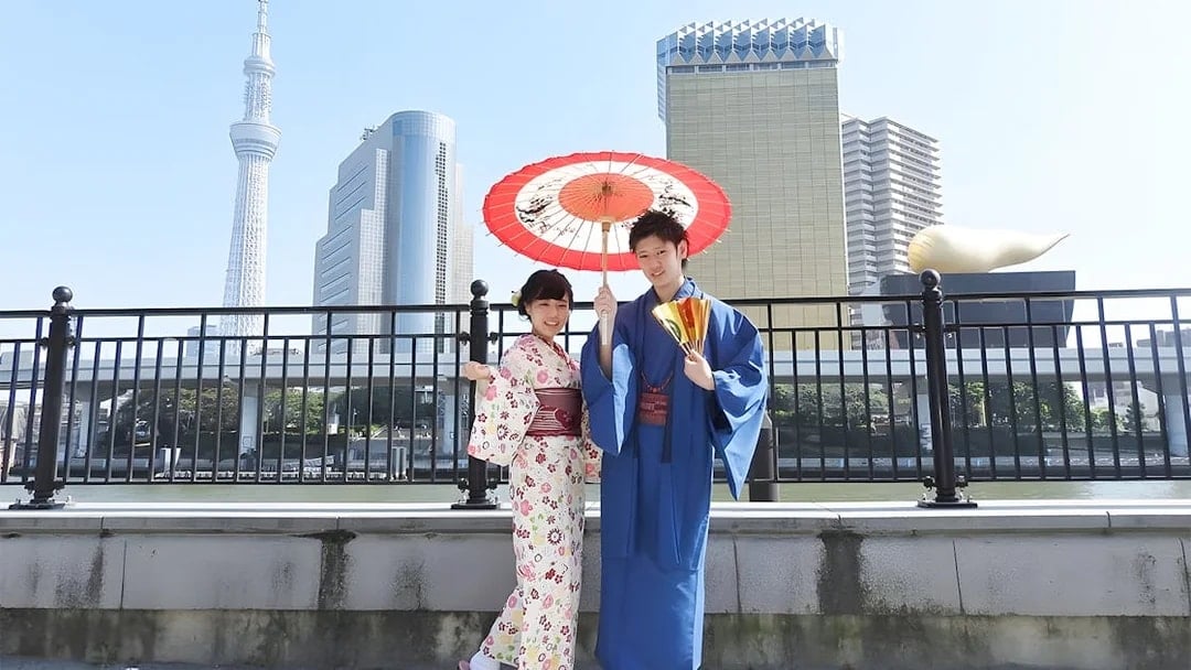 Couple in kimonos with umbrella at Asakusa, Tokyo Skytree in background.
