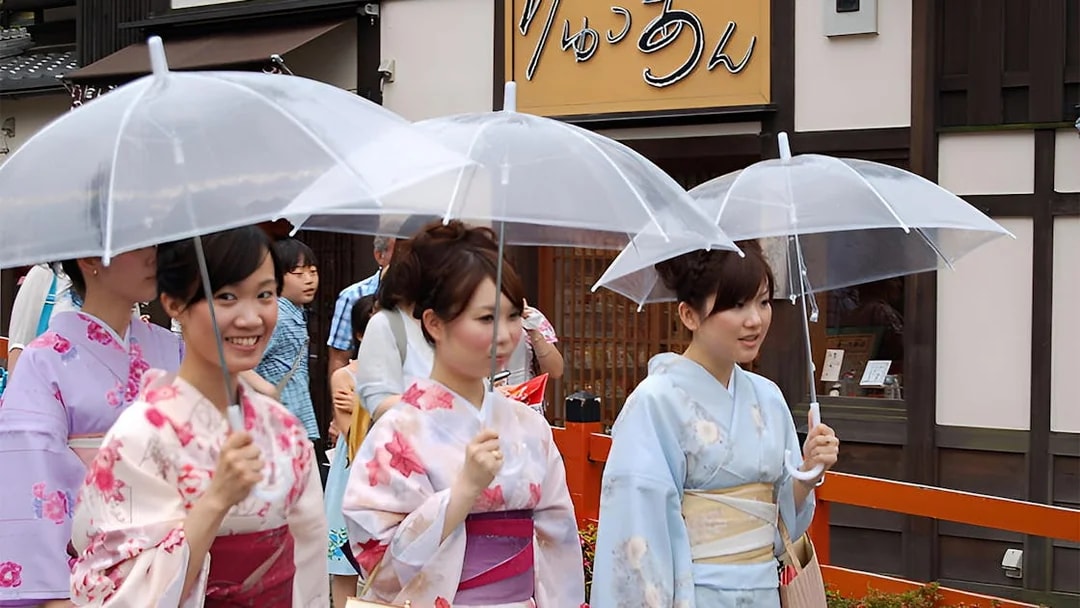 Women in kimonos with umbrellas walking in Asakusa, Tokyo.