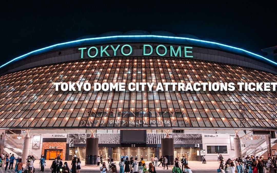 Tokyo Dome entrance illuminated at night, promoting city attractions ticket.