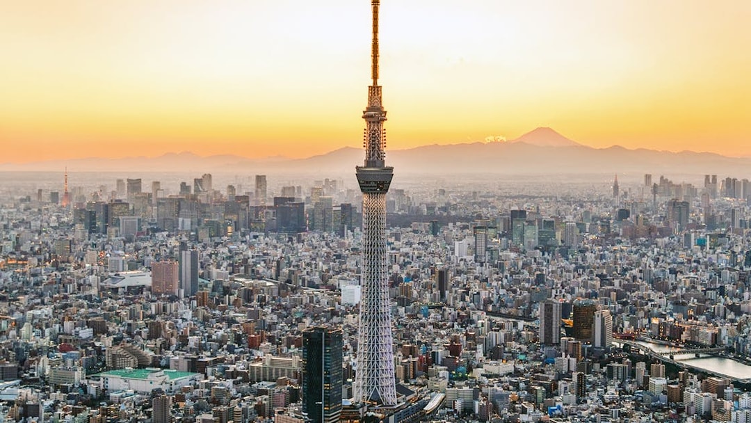 Tokyo Skytree towering over cityscape at sunset.