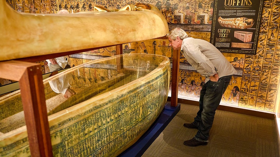 Visitor examines Egyptian sarcophagus at Tomb of the Pharaoh exhibit, Cairns.