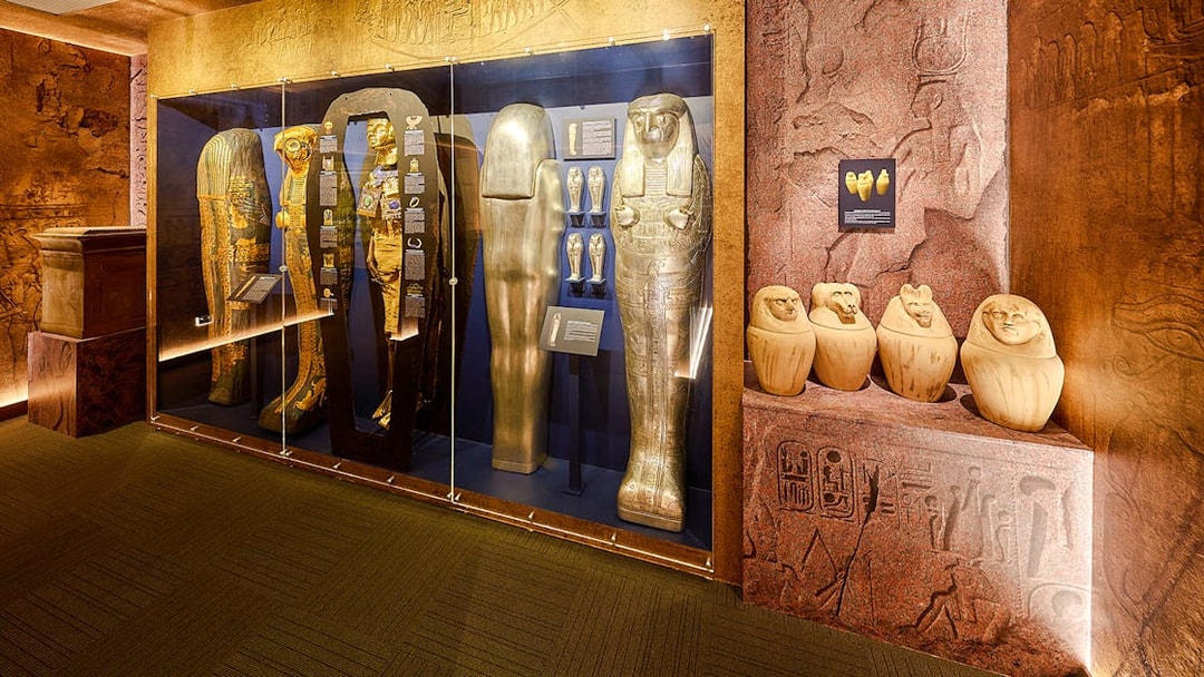 Golden sarcophagi and canopic jars in glass case at Tomb of the Pharaoh exhibit.
