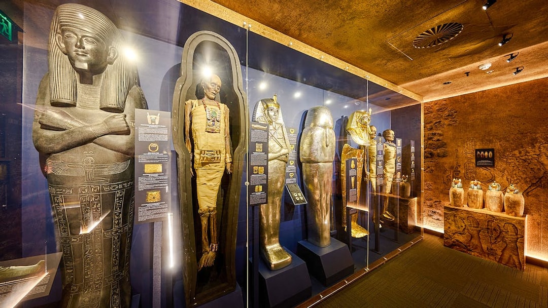 Ancient Egyptian sarcophagi and mummy cases in the Tomb of the Pharaoh exhibit.