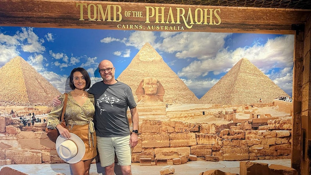 Couple posing in front of Great Pyramids and Sphinx backdrop at Tomb of the Pharaohs exhibit.