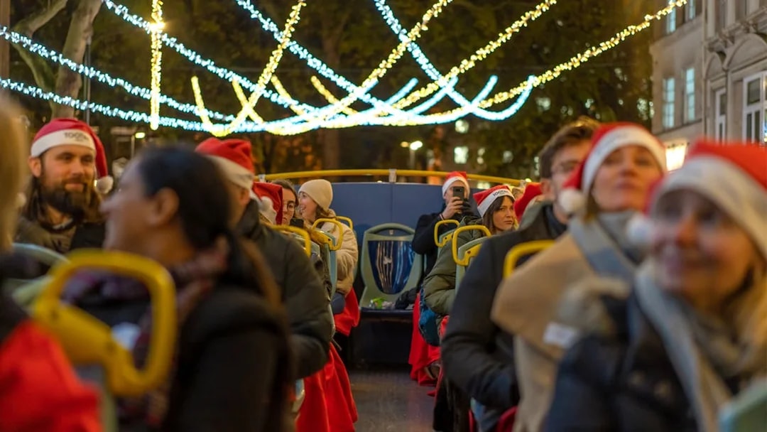 Passengers in Santa hats on a Tootbus enjoying London Christmas lights.