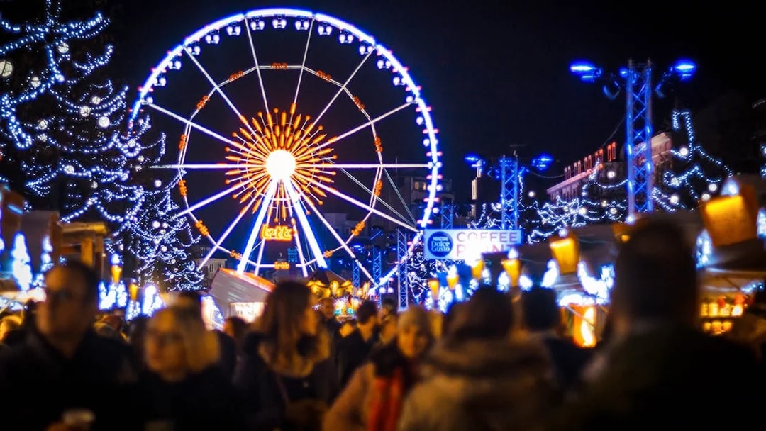 Ferris wheel and festive lights at a bustling Christmas market.
