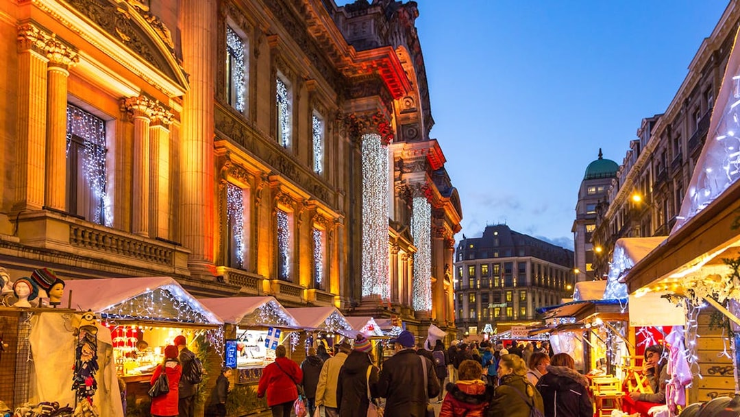 London Christmas market with festive lights and decorated stalls on illuminated street.