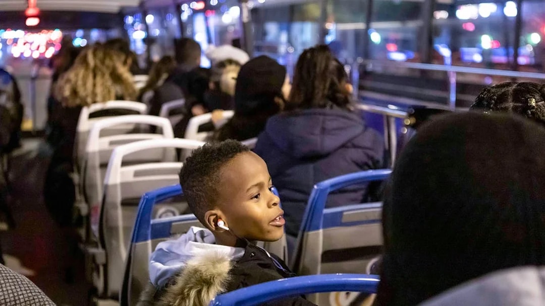 Bus passengers enjoying a Christmas lights tour at night.