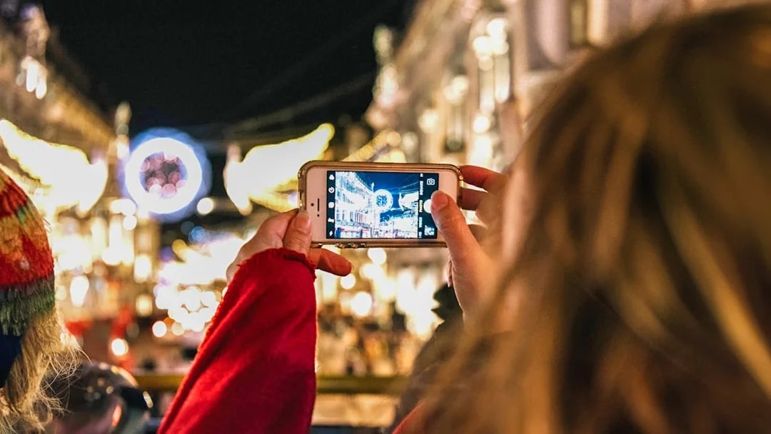Person photographing London Christmas lights from Tootbus tour.