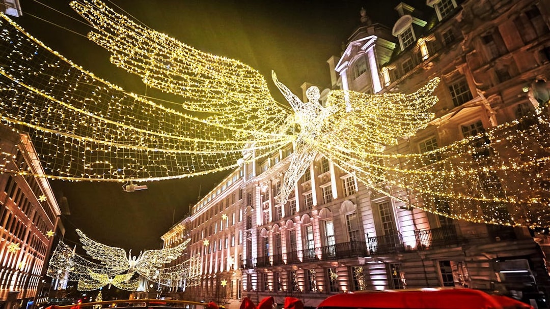 Double-decker bus under London Christmas lights on Tootbus route.