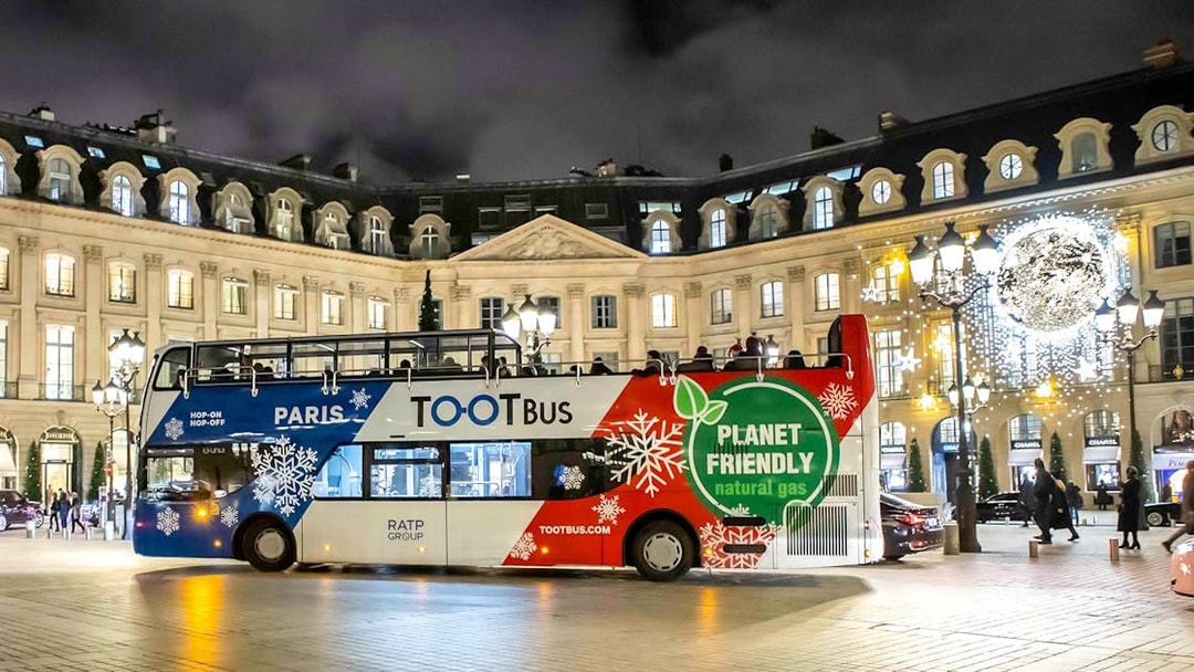 Paris Christmas Tootbus in festive lights at Place Vendôme.
