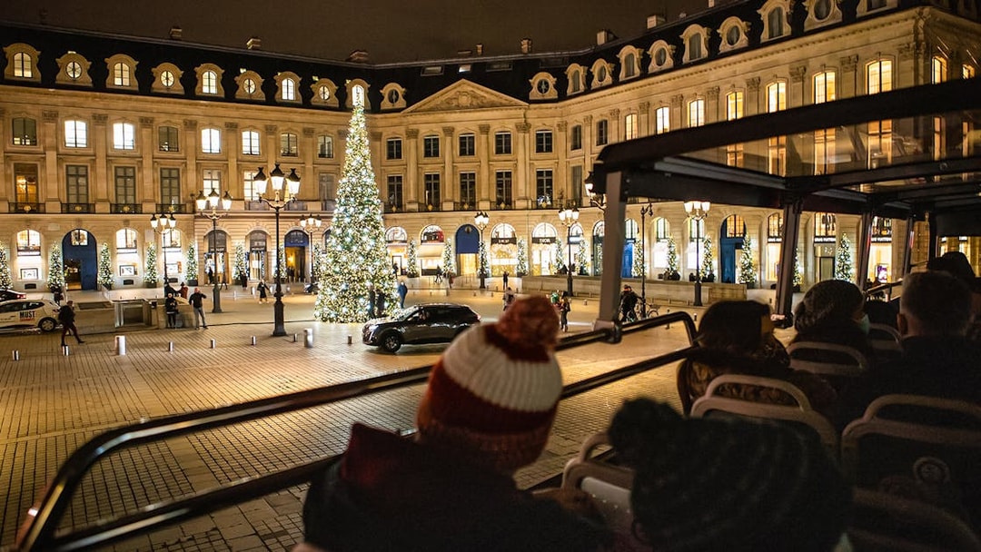 Tourists on a bus tour view Christmas lights at Place Vendôme, Paris.
