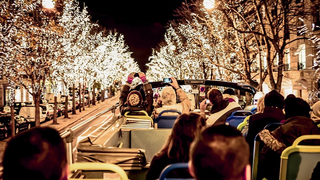 Tourists on open-top bus viewing Christmas lights in Paris.