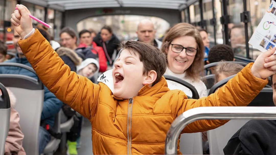 Joyful child celebrating quiz win on Tootbus tour in Paris.